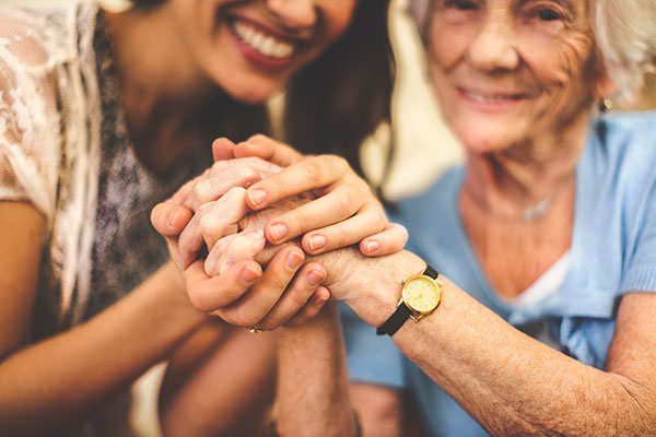Close-up of a smiling nurse holding a senior woman's hand